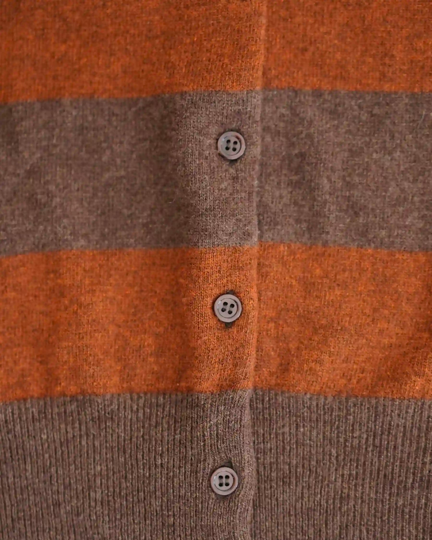 Close-up of the Merino Cardigan in Foxtail by Pyne and Smith Clothiers, featuring wide brown and burnt orange stripes, four round brown buttons, and crafted from soft Italian merino wool for a luxurious feel.