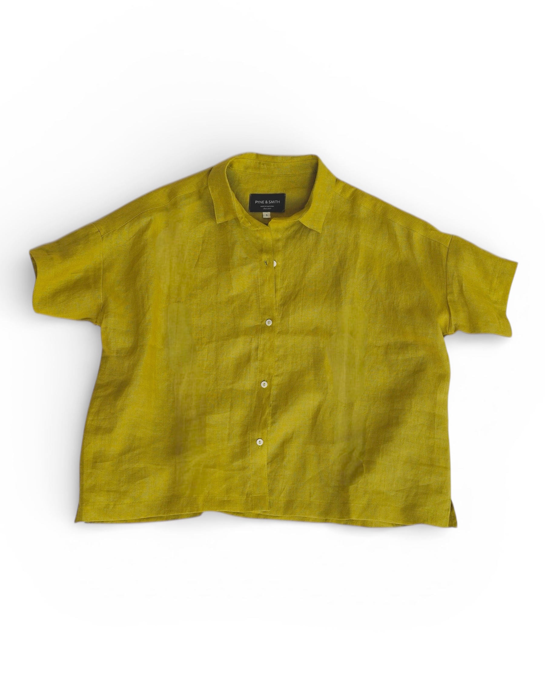 The Cropped Linen Blouse No.24 in Apple by Pyne and Smith Clothiers is an oversized, short-sleeved button-up shirt made from linen, shown laid flat on a white background.