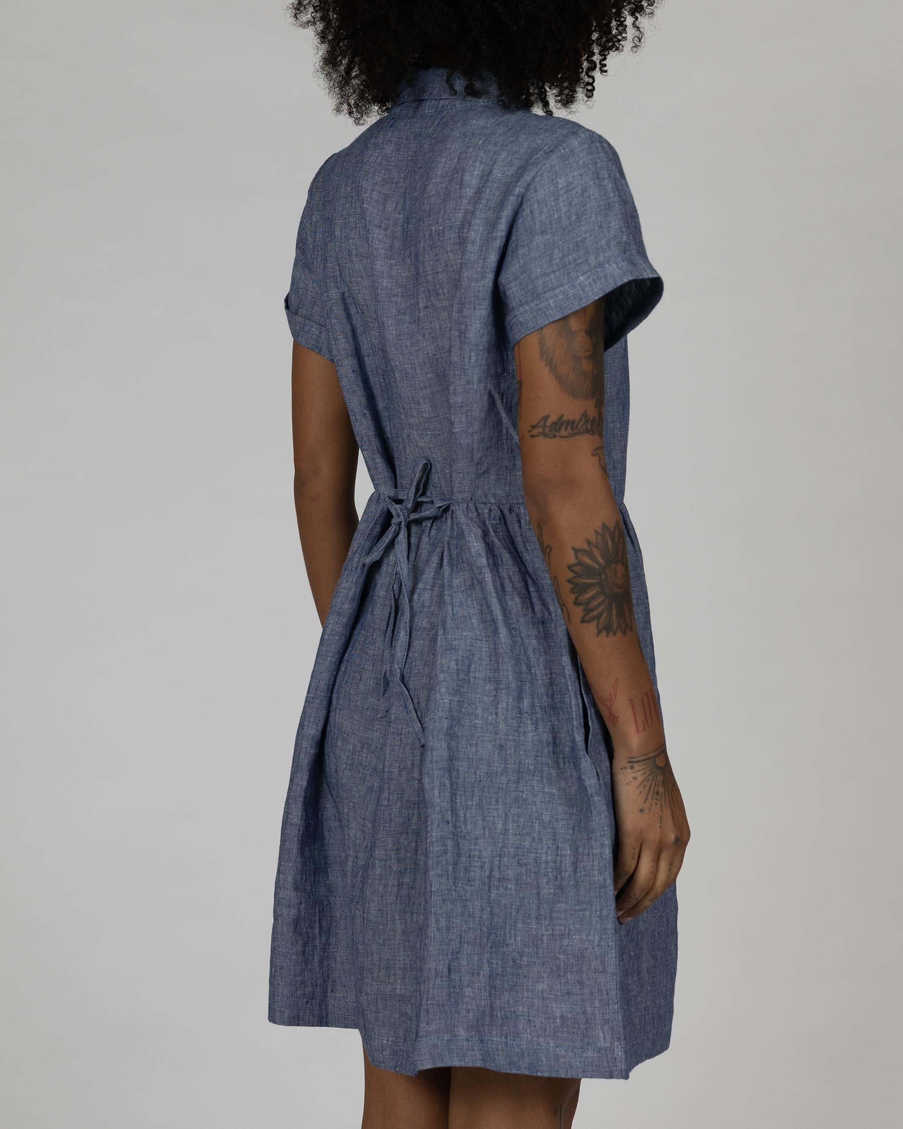 Back side view of model wearing dress model number 23 in Oxford chambray linen