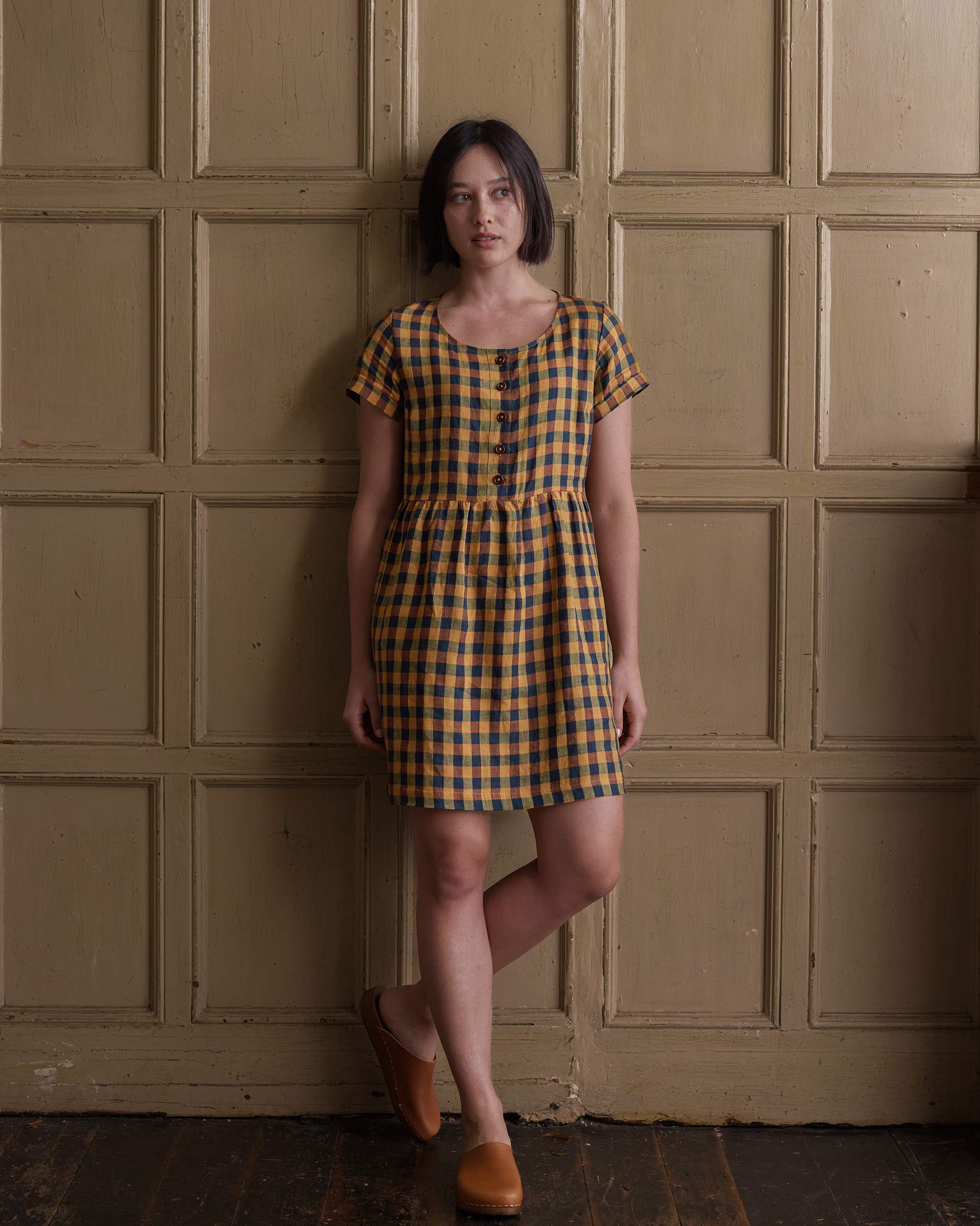 Front view of model wearing linen button up knee length dress in Basque Check