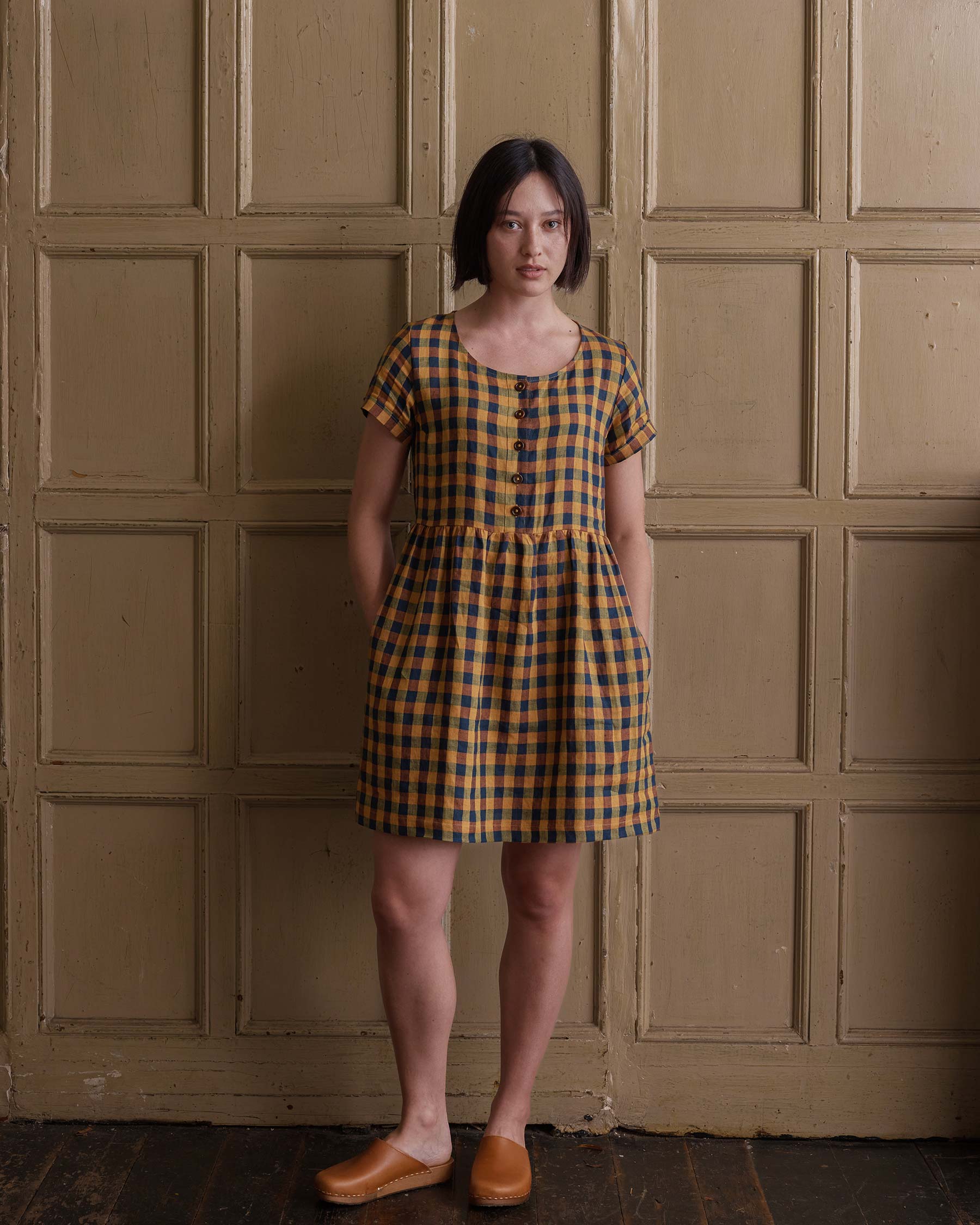 Front view of linen button up knee length dress with pockets in basque check