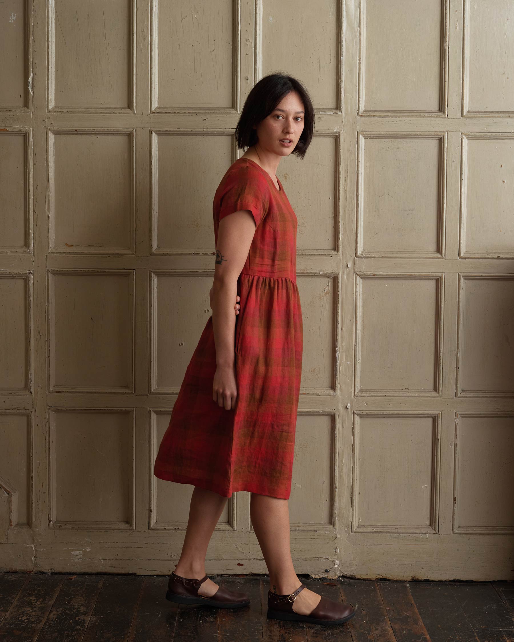 Model showing side view of linen midi day dress in red Paloma Check with pockets