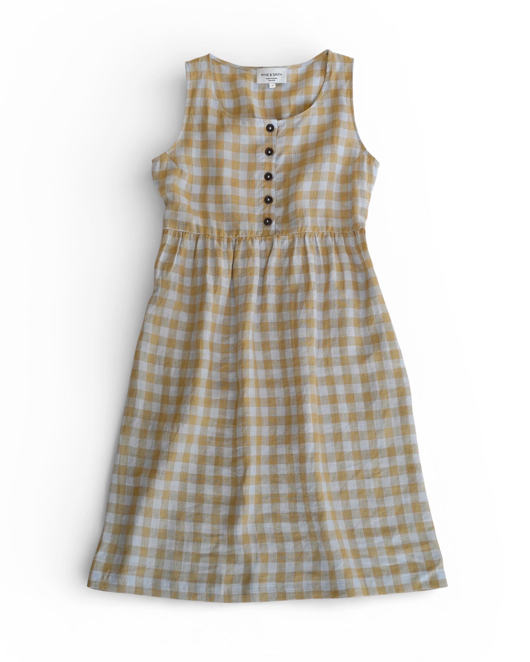 The Pyne and Smith Clothiers No.24 Sleeveless, button up Linen Dress in St. Agnes Check features a yellow and white check pattern, fitted bodice, gathered waist, and dark buttons. Shown laid flat on a white background.