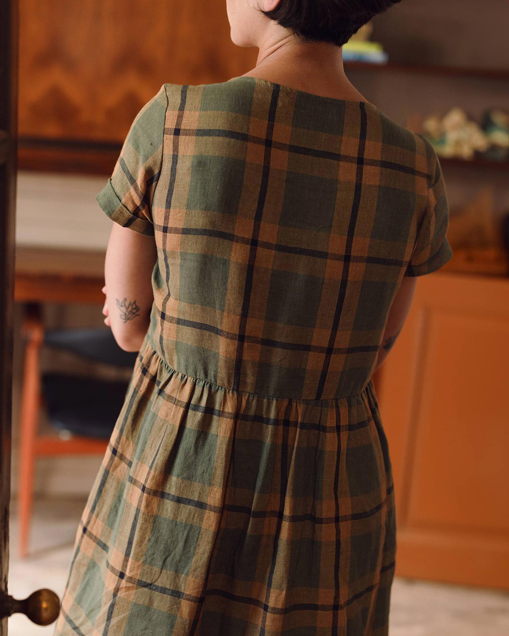 Close up back view of green, tan and black stripe The George Plaid linen tea dress showing short sleeves with folded cuffs